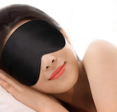 Person wearing a black 3d black out sleeping mask with a plain background